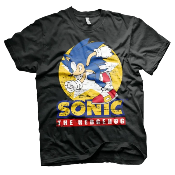 Sort T-shirt med en dynamisk illustration af Sonic, der løber med sit klassiske blå look, røde sko og hvide handsker. Baggrunden har en gul cirkel med en let slidt effekt, og teksten "Sonic The Hedgehog" står i gule og røde bogstaver.